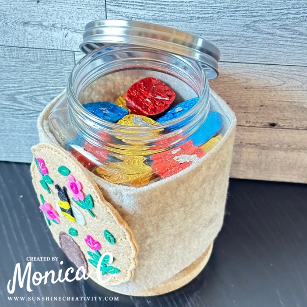 Felt & Stitch Beehive on a jar filled with chocolates.